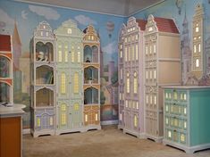 a room filled with lots of doll houses and walls painted in pastel blue, pink, yellow and green