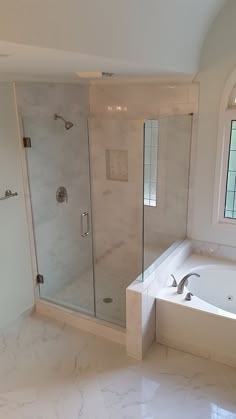 a bathroom with a large tub and walk in shower next to a window on the wall