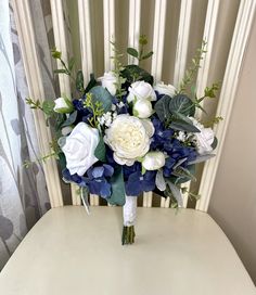 a bridal bouquet sitting on top of a white table next to a window curtain