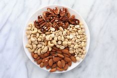 nuts in a white bowl on a marble surface