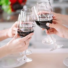 three people are toasting with red wine glasses