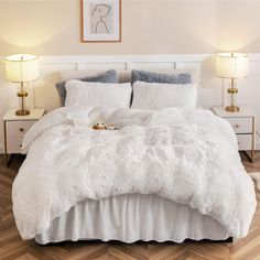 a bed with white comforter and pillows in a bedroom next to two nightstands