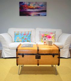 a white couch sitting next to a wooden trunk on top of a table