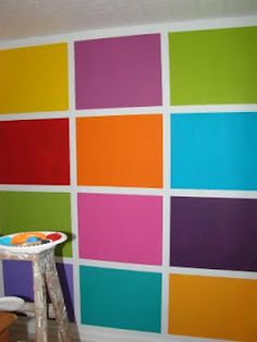 a room that has some colorful squares painted on the wall and a ladder in front of it