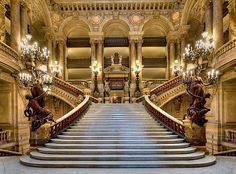 an ornate staircase with statues and chandeliers in a large palace like building,