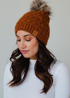 a woman wearing a brown hat with a fur pom