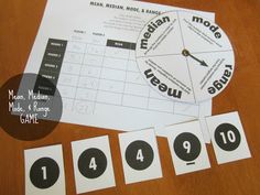 a wooden table topped with paper cutouts and numbers next to a clock that reads mean, median, mode & range