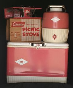 an old pink and white ice chest sitting on top of a black background with other items