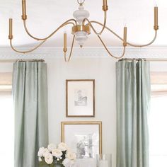 a dining room table with flowers and candles on it in front of two framed pictures