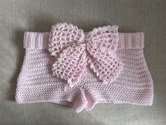 a pink knitted bow on top of a white blanket