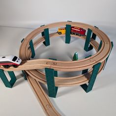 a toy train set is shown on a white surface with green rails and wooden tracks