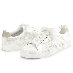 a pair of white shoes with flowers on the side and one shoe has a bow at the top