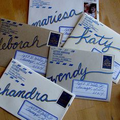 several envelopes with blue ink on them sitting on a wooden table next to each other