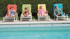 three elderly people sitting in lawn chairs next to a swimming pool