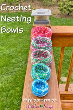 the crochet nesting bowls are sitting on top of a wooden bench with grass in the background