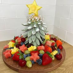 a christmas tree made out of fruit on a wooden platter with a yellow star