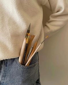 a person holding some paint brushes in their pocket