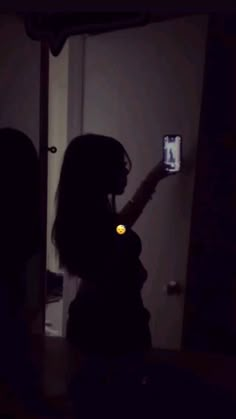 a woman is taking a photo with her cell phone at night in front of the door