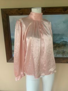 "In great condition! Great pink silky material. Buttons in the back of the neck. 100% polyester  Measurements lying flat: Bust: 20\" Waist: 20\" Length: 22.5\" All sales final. Note: items are described as accurately as possible. All of my items are used unless otherwise stated. Vintage items are sized differently than modern clothing so PLEASE make sure to check the measurements I have provided in order to make the best purchasing decision.  Vintage clothing may show signs of general wear. If there are holes, rips or major flaws I will do my best to mention them in the main description. As always, feel free to ask questions!" Spring Silk Stretch Blouse, Feminine Long Sleeve Satin Tops, Pink Satin Top For Evening, Stretch Silk Long Sleeve Tops, Pink Stretch Elegant Blouse, Feminine Pink Stretch Blouse, Pink Long Sleeve Satin Top, Long Sleeve Pink Satin Top, Pink Satin Long Sleeve Tops