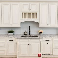 a kitchen with white cabinets and marble counter tops