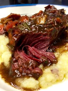 a close up of food on a plate with meat and gravy in sauce