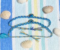 several seashells on a blue and white striped tablecloth with beads, chains, and bracelets