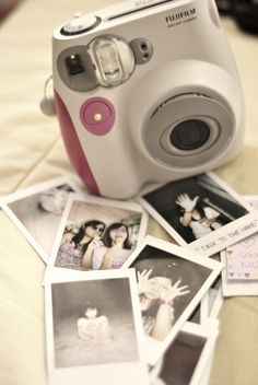 a polaroid camera sitting on top of a bed next to some pictures and cards