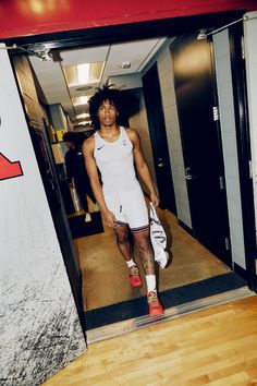 a man in white shirt and shorts walking into an elevator