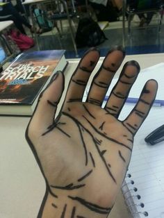 a person's hand with lines drawn on it in front of a notebook and pen