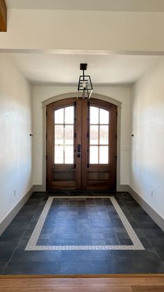 an empty room with two double doors and a light fixture hanging from the ceiling above it