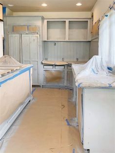 an empty kitchen is being remodeled with white cabinets and blue tape on the counter tops