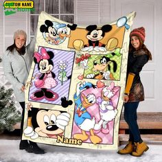 two women standing next to each other holding up a blanket with cartoon characters on it