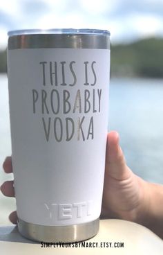 a person holding up a white yeti cup with the words, this is probably vodka