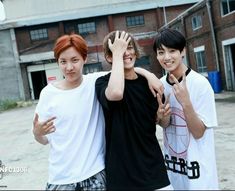 three young men standing next to each other with their hands in the air and smiling