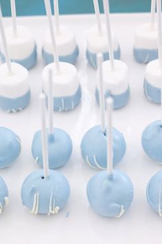 blue and white cake pops are arranged on a tray