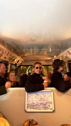 some people are sitting in the back of a bus and one person is wearing sunglasses