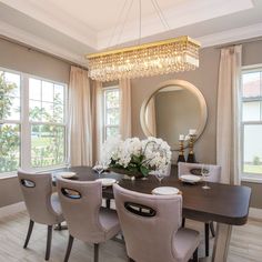 a dining room table with chairs and a chandelier hanging from it's ceiling