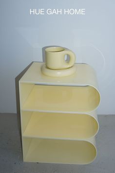 three yellow shelves stacked on top of each other with a coffee cup in the middle