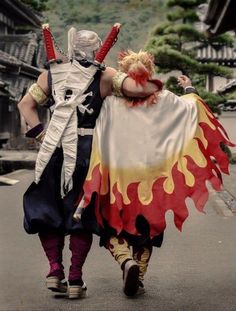 two people dressed in costumes walking down the street with their arms wrapped around each other