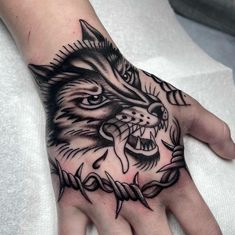 a person's hand with a tattoo on it and a wolf head in the middle