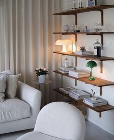 a living room with two white chairs and some shelves filled with books, vases and other items