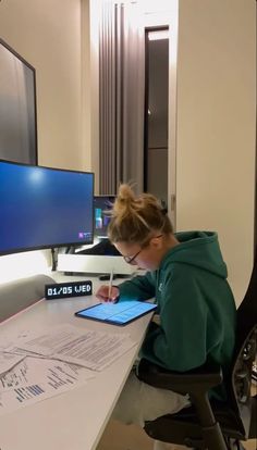 a woman sitting at a desk using a tablet computer