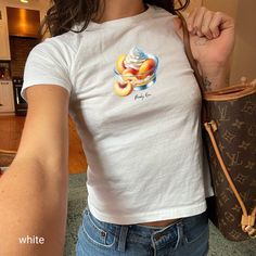 "🍑 Embrace the sweet vibes of yesteryear with our Peachy Keen Graphic T-Shirt! Perfectly aligning with the Y2K revival and coquette style trends, this adult baby tee is a must-have for your summer wardrobe. It features a nostalgic, high-quality print of luscious peaches topped with whipped cream, set against a soft, vintage-style backdrop. Ideal for casual outings or stylish lounging, this tee promises comfort and chic in one delightful package. Pair it with your favorite jeans or a flirty skirt to complete the look. Get ready to turn heads and feel peach-perfect all season long! 🍨  Looking for a graphic baby tee nostalgic of the 90s? Bring your Y2K outfit dreams to life with our newest collection. This classic baby tee will fit like a well-loved favorite from its first wear.  ✨PLEASE NO Peach Top, Peach Shirt, Baby Graphic Tees, Peaches N Cream, Graphic Top, Baby T Shirts, Y2k Style, Crop Shirt, Infant Tees