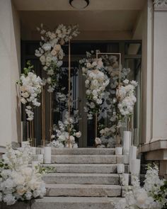 white flowers and candles are on the steps leading up to an entrance with glass doors