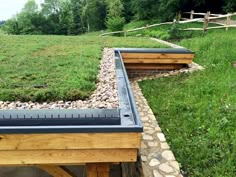 a green roof on top of a building in the middle of some grass and rocks