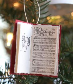 an ornament hanging from a christmas tree with sheet music on it's book