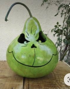 a green pear with a face drawn on it's side sitting on a wooden table