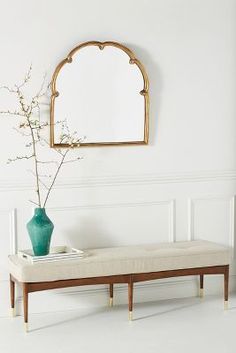 a bench with a vase and mirror on the wall