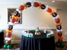 an arch made out of balloons with footballs on it in the middle of a room