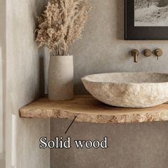 a bathroom sink sitting on top of a wooden counter next to a vase with dry grass in it